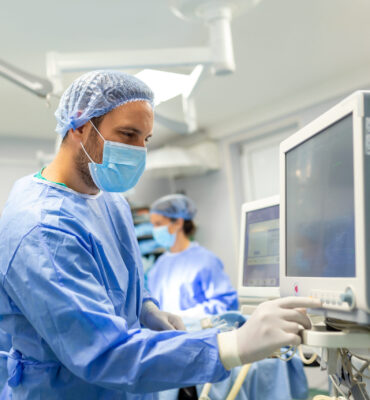 Medical ventilator being monitored by anaesthetist. surgeon using monitor in operating room.