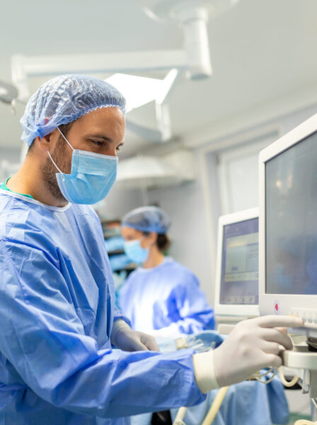 Medical ventilator being monitored by anaesthetist. surgeon using monitor in operating room.